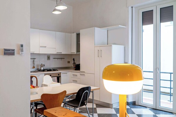 A modern kitchen with white cabinets, a dining area with a table and chairs, and a large window with a view.