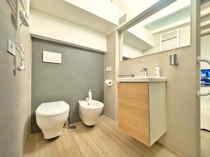 Een moderne badkamer met toilet, hygiëneschuimer en wastafel.