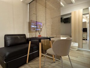 Een moderne kamer met een zwarte leren bank, een houten tafel met een kaars en een grijze stoel.