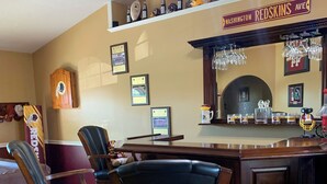 Un área de bar con sillas de madera, una barra con vasos y un letrero que dice 'Washington Redskins Ave'.