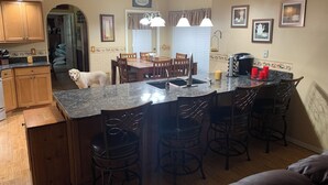 Una cocina con una isla central, armarios de madera y un comedor con sillas.