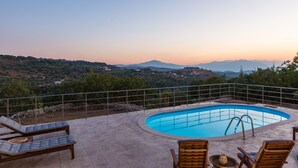 Una piscina con sillones de descanso y vistas al campo.