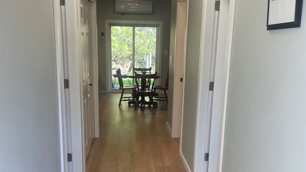 A hallway with wooden flooring, white walls, and a 'Welcome' sign. - Quiet getaway in the forest close to beach/lakes/Mt Washington and great food. (Qualicum Beach)