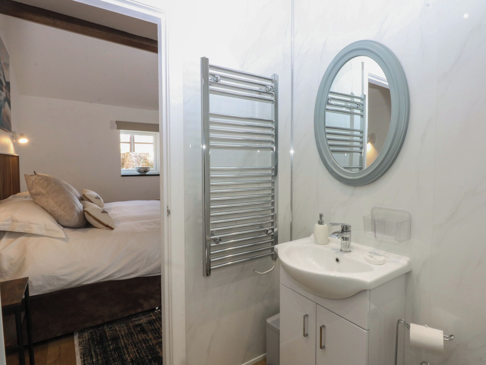 Un baño moderno con lavamanos, espejo y toallero blancos.