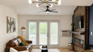 En moderne stue med spiseplads, ventilator i loftet og pejs.