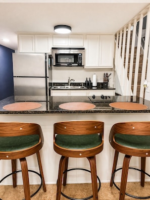 A kitchen with white cabinets, stainless steel appliances, a microwave, and a refrigerator. There are three wooden bar stools with green cushions. - 2 Bedroom Condo ON Lake Hamilton! Sleeps 6! (Hot Springs)