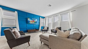 Ein modernes Wohnzimmer mit blauer Akzentwand, einem Flachbildfernseher und einem Ecksofa.