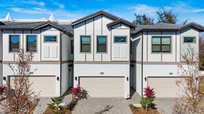 A modern multi-story residential building with a symmetrical facade, large windows, and garage doors. - 5Br & 5Ba Paradiso Grande - Walk To Seaworld 10507 (Orlando)