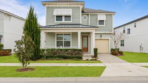 A two-story residential building with a front porch, a garage, and a well-maintained lawn. - 6Bd Villa W Spa, Star Wars Cinema & Gameroom 2088 (Kissimmee)
