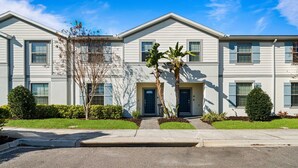 A multi-story residential building with a symmetrical facade, a central entrance, and a well-maintained lawn. - Modern 5Br Downstairs Room, Pool & Lazy River 2402 (Kissimmee)