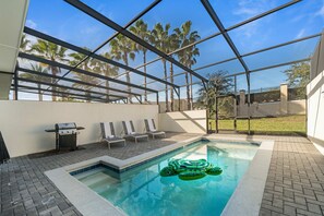 A pool with a floating toy, lounge chairs, and a grill. - Modern 5Br Downstairs Room, Pool & Lazy River 2402 (Kissimmee)