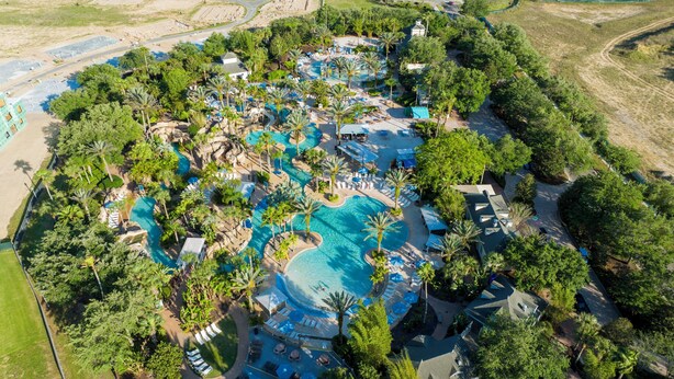 Vue aérienne d’un complexe hôtelier doté de plusieurs piscines, de palmiers et d’espaces de détente.