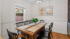 A dining area with a wooden table, black chairs, a potted plant, and framed artwork on the wall. - Family-Friendly 3BR Home Near DC (Arlington)