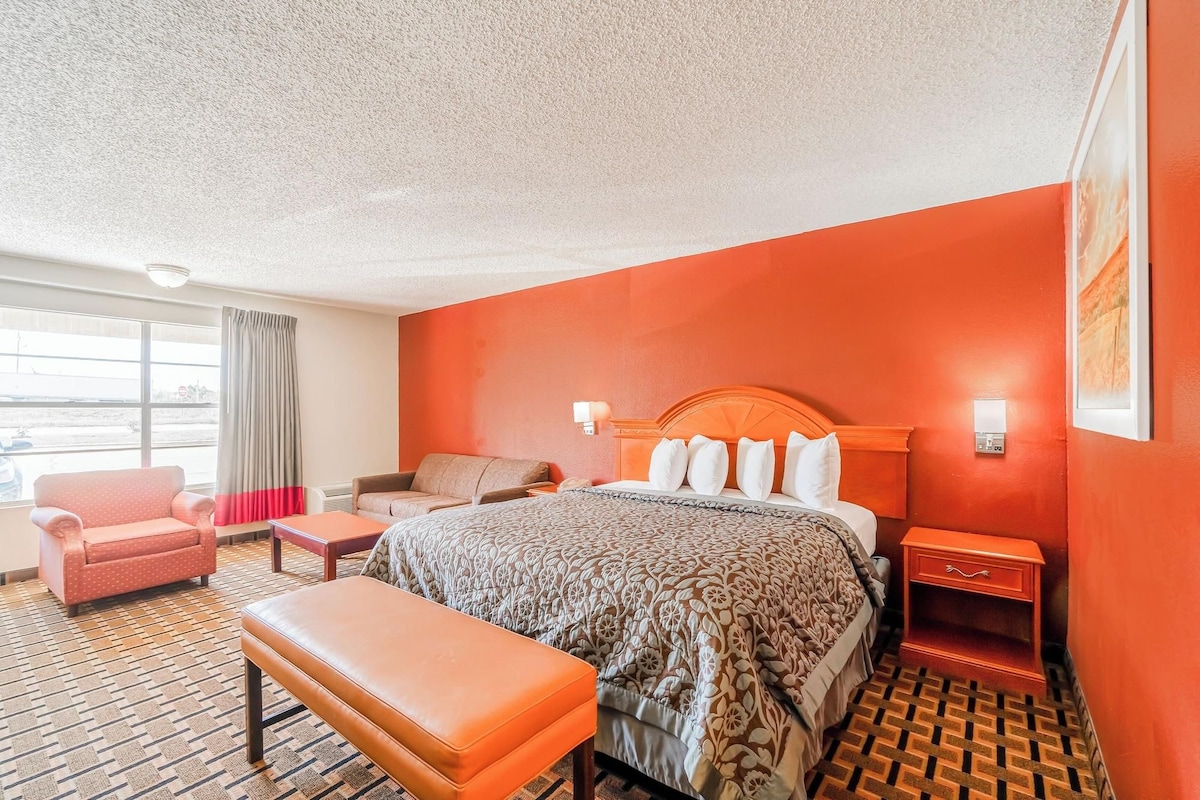 Une chambre d’hôtel avec un grand lit, un canapé, un fauteuil et une petite table.