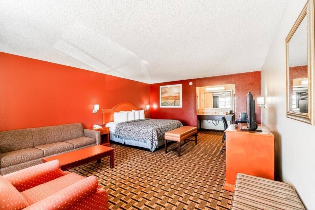 A hotel room with a bed, a sofa, a desk, a television, and a mirror.