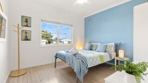 Un dormitorio con cama, ventana, lámpara de pie y una planta.