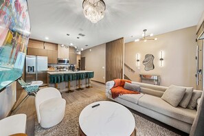 Ein modernes Wohnzimmer mit Sofa, Sesseln, einem Couchtisch und einer Küchenzeile mit Esstisch.