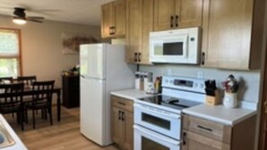 Una cocina con armarios de madera, microondas, refrigerador y horno.