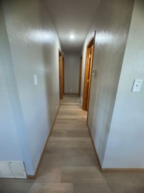 A narrow hallway with wooden doors and a light-colored floor.