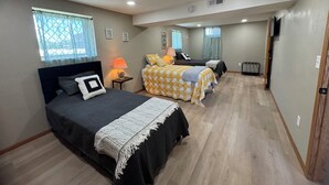 Un dormitorio con dos camas, una mesita de noche, una lámpara y una ventana con cortinas.