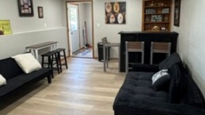 Una sala de estar con un sofá negro, chimenea y estantería.