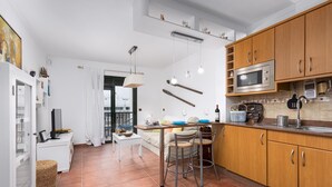 A modern kitchen with wooden cabinets, a stainless steel microwave, and a dining area with a table and chairs. - Home2Book Elegant City Escape with Terrace (Puerto Lajas)