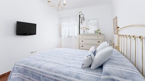 A bedroom with a bed, a dresser, a television, and a chandelier. - Home2Book Elegant City Escape with Terrace (Puerto Lajas)