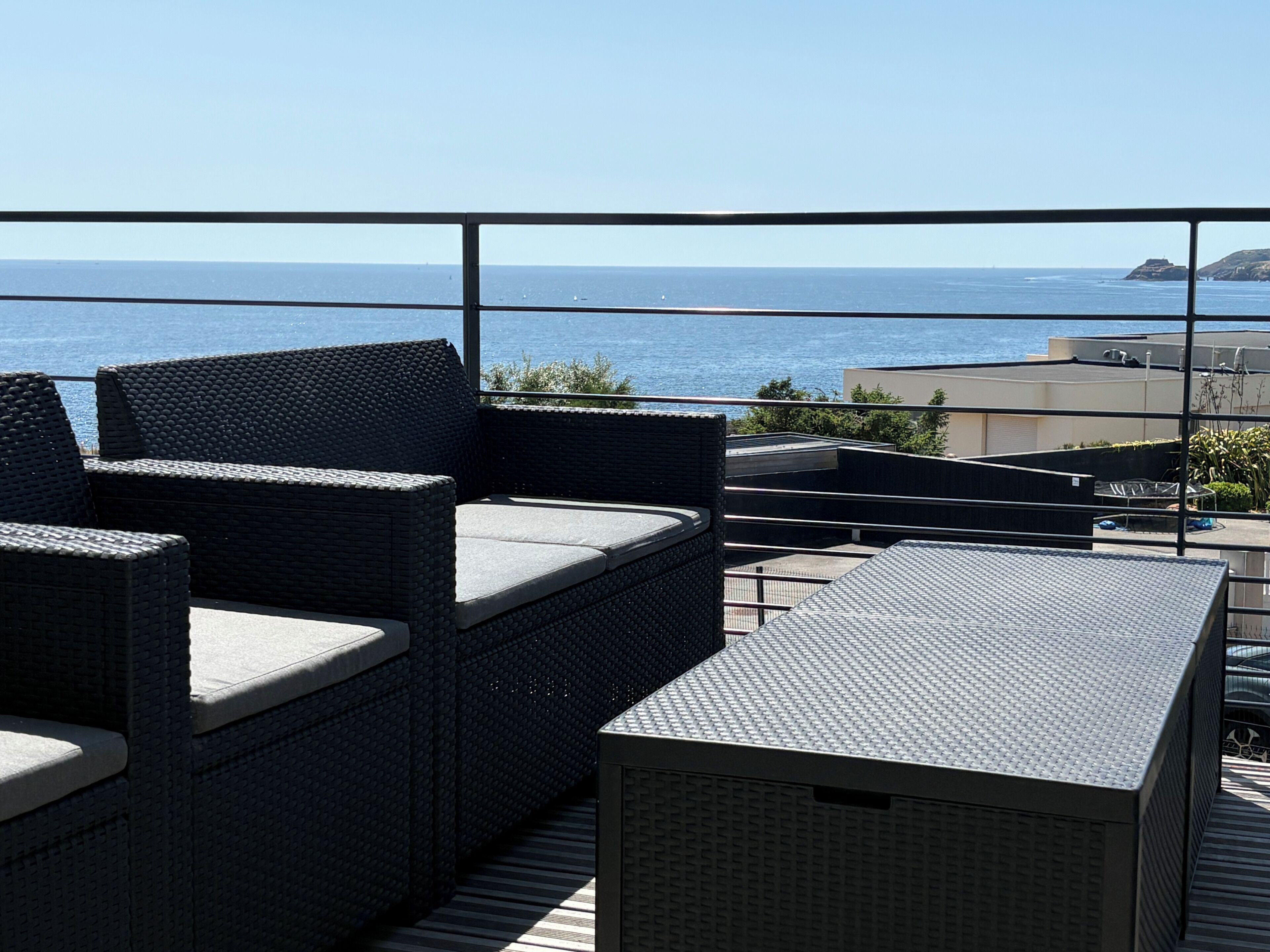 A balcony with wicker furniture overlooking a body of water.