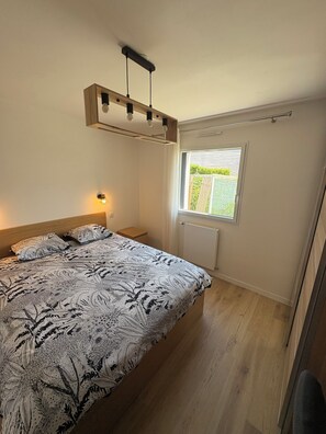 Ein Schlafzimmer mit einem Bett, einem Nachttisch, einem Fenster mit Aussicht und einer Deckenleuchte.