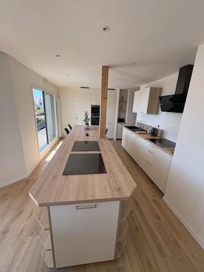 A modern kitchen with a central island, white cabinetry, and a view to the outside.