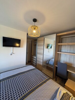 A bedroom with a bed, a TV mounted on the wall, a wardrobe, and a desk. - Villa Tregana Beach: comfort and immersion in an idyllic landscape (Locmaria-Plouzané)