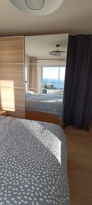 A bedroom with a bed, a view of the sea, and a balcony.