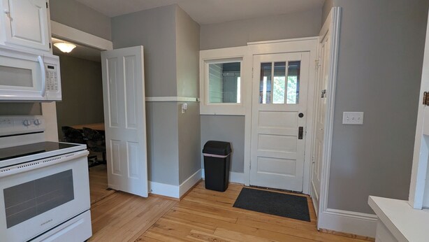 A kitchen with white appliances, a wooden floor, and a door with a window. - Upper 2-bedroom apartment near down-town Chippewa Falls (Chippewa Falls)