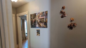 A hallway with wooden flooring, a ceiling light, and a wall with a painting and decorative elements. - Upper 2-bedroom apartment near down-town Chippewa Falls (Chippewa Falls)
