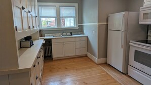 A kitchen with white cabinets, a double sink, a refrigerator, and an oven. - Upper 2-bedroom apartment near down-town Chippewa Falls (Chippewa Falls)