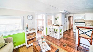 A spacious living area with a kitchen, a dining table, and a green accent wall. - 466 Marlin Dr. - Nice 2 Bedroom with Beach Chair Service Included! (Panama City Beach)