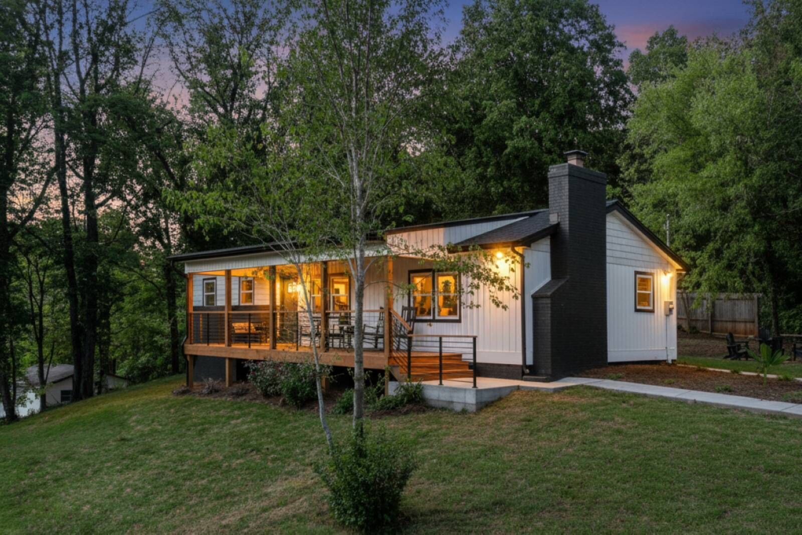 Et moderne hus med to etager, en overdækket veranda og et stort vindue med udsigt over haven.