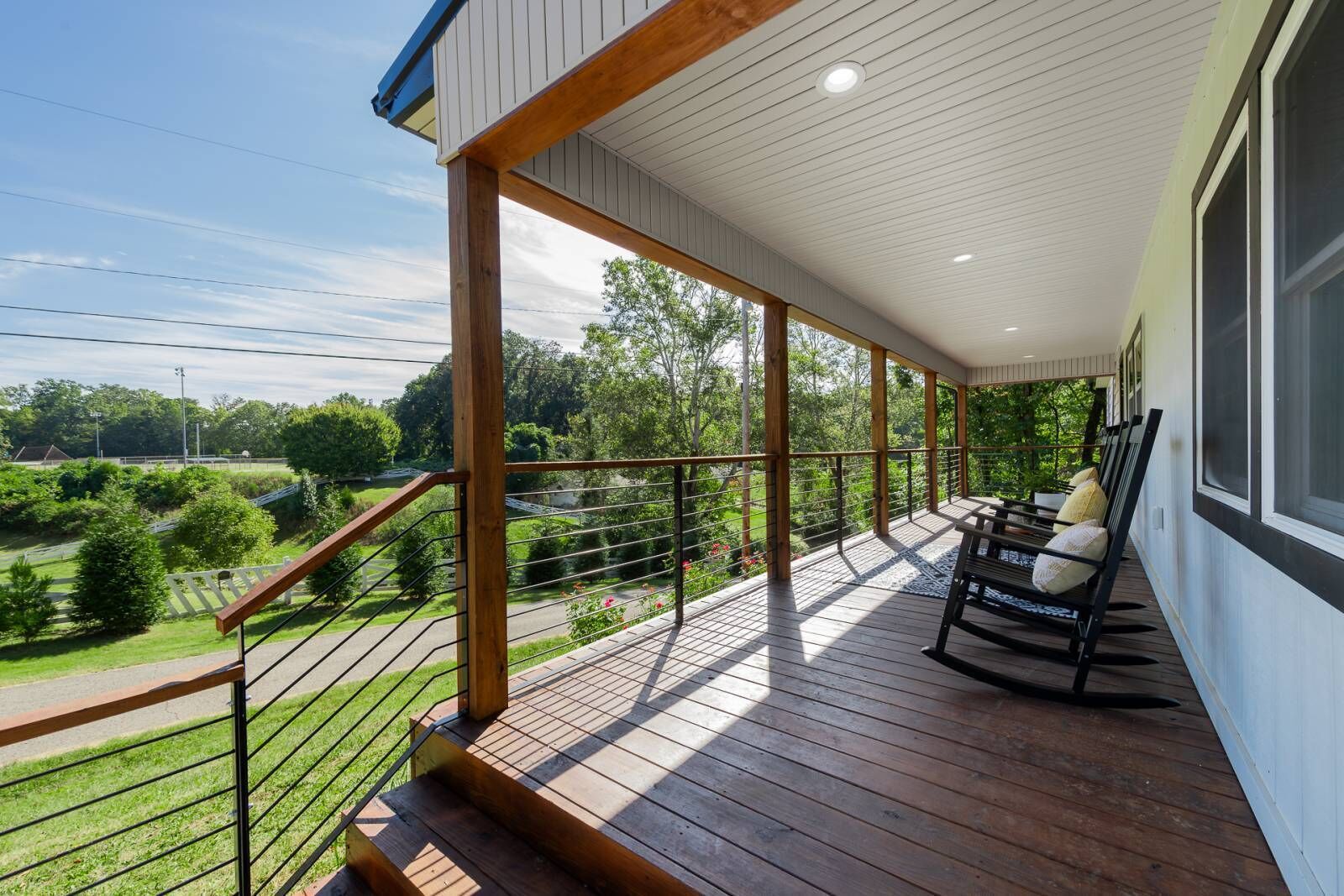 Une terrasse en bois avec une rambarde, un banc et une vue sur un paysage verdoyant.