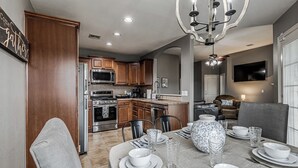 A modern kitchen with wooden cabinets, stainless steel appliances, and a dining area set for four. - 3-bedroom house in Coweta close to Broken Arrow (Coweta)