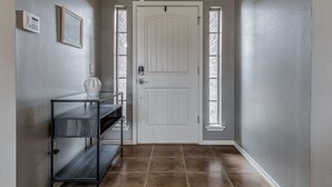 A hallway with a white door, a small table with a vase, and a bench. - 3-bedroom house in Coweta close to Broken Arrow (Coweta)