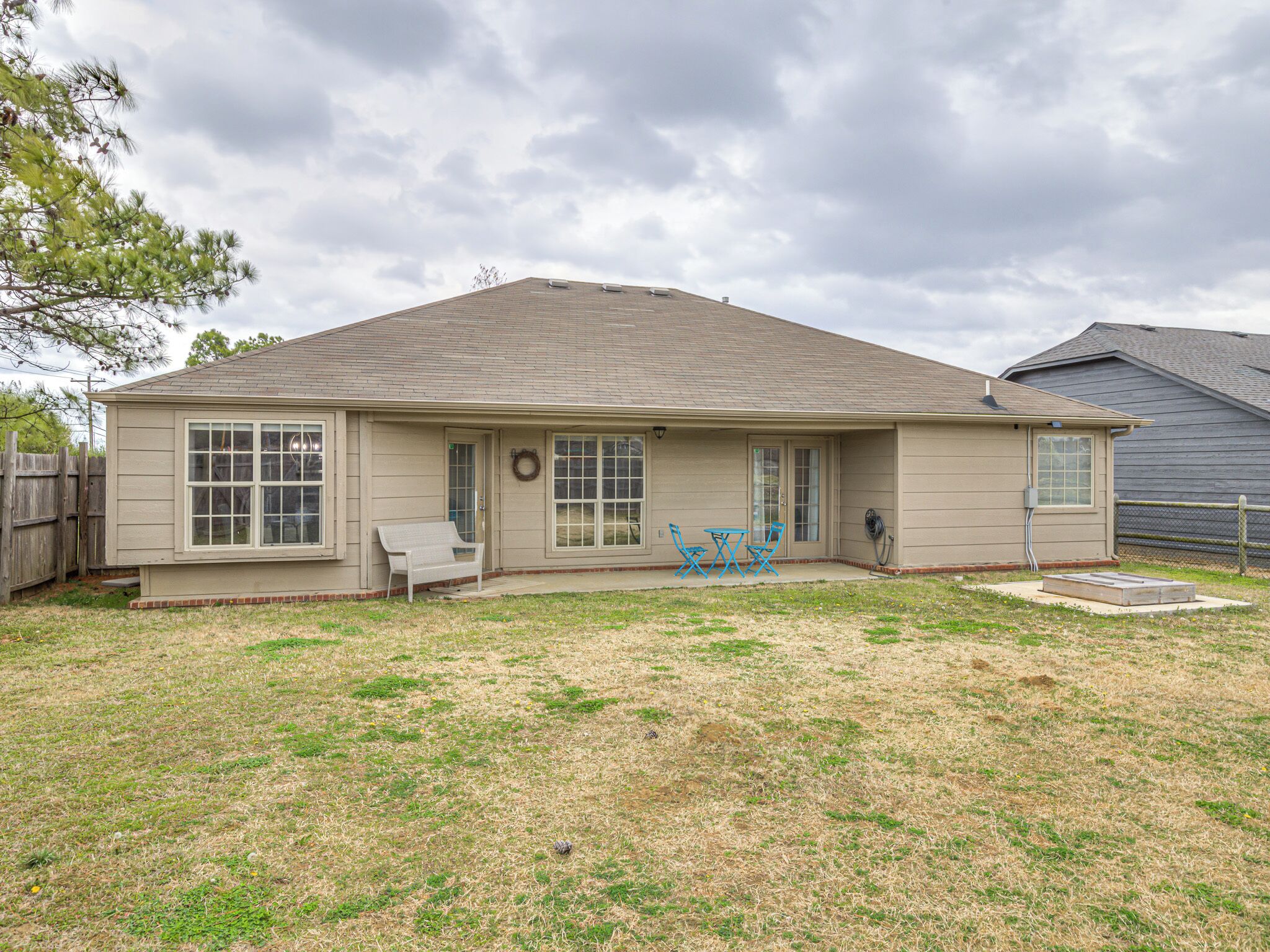 A single-story house with a front porch, a small patio, and a fenced yard.