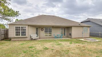 A single-story house with a front porch, a small patio, and a fenced yard.
