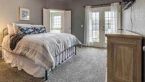 A bedroom with a bed, a ceiling fan, a wooden dresser, and a TV mounted on the wall. - 3-bedroom house in Coweta close to Broken Arrow (Coweta)