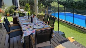 Un patio exterior con piscina, mesa y sillas cubiertas.