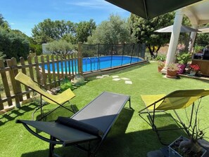 A backyard with a swimming pool, two lounge chairs, and a wooden fence. - Pleasant villa, well exposed (Régusse)