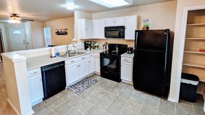 A modern kitchen with white cabinetry, a black refrigerator, a microwave, and a dishwasher. - Cozy 2-bedroom home, North East San Antonio (San Antonio)