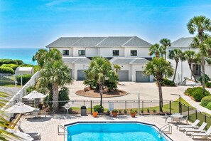 Un hôtel doté d’une piscine, de palmiers et offrant une vue sur l’océan.
