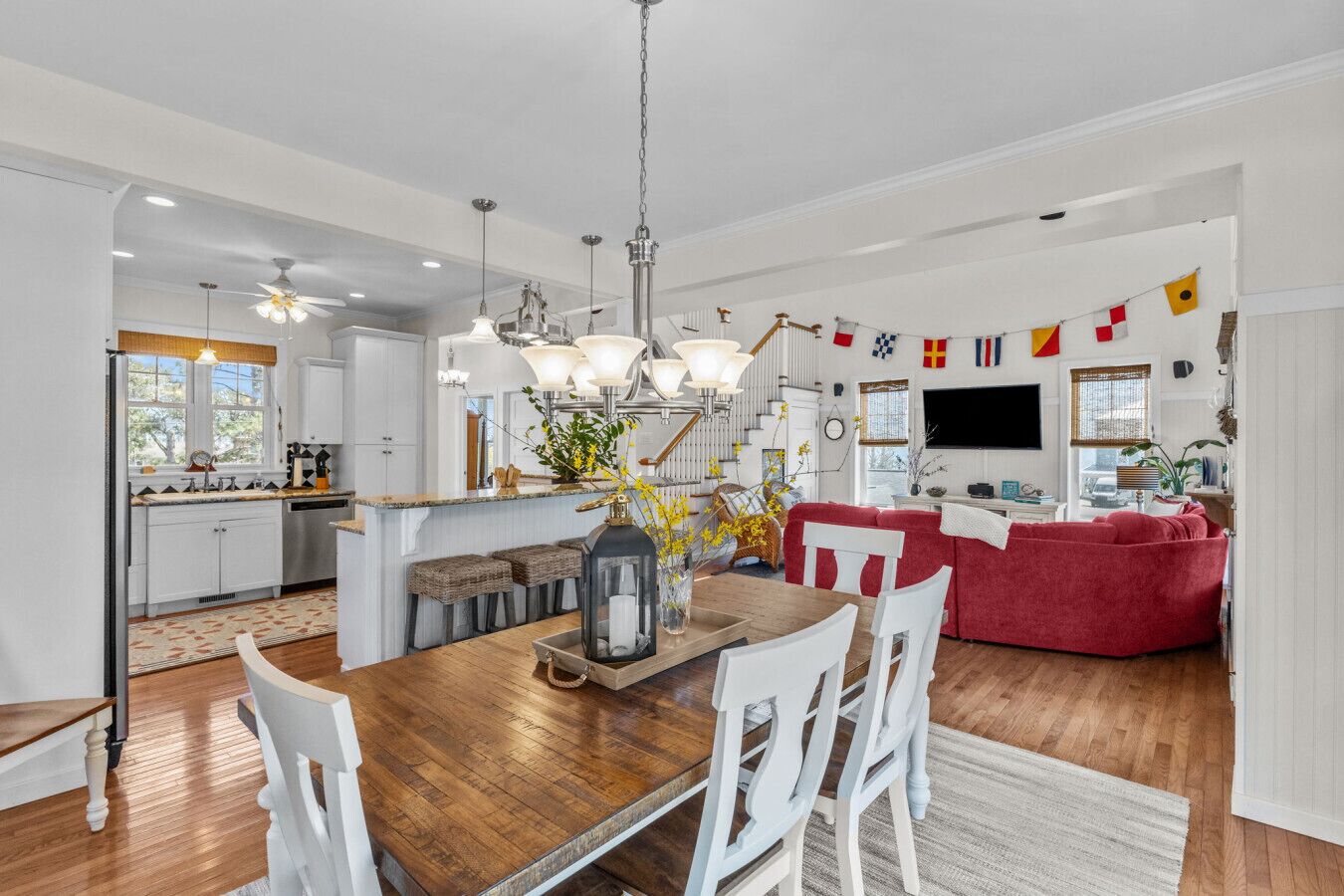 Une cuisine moderne avec des meubles blancs, un îlot central en bois et des luminaires suspendus.