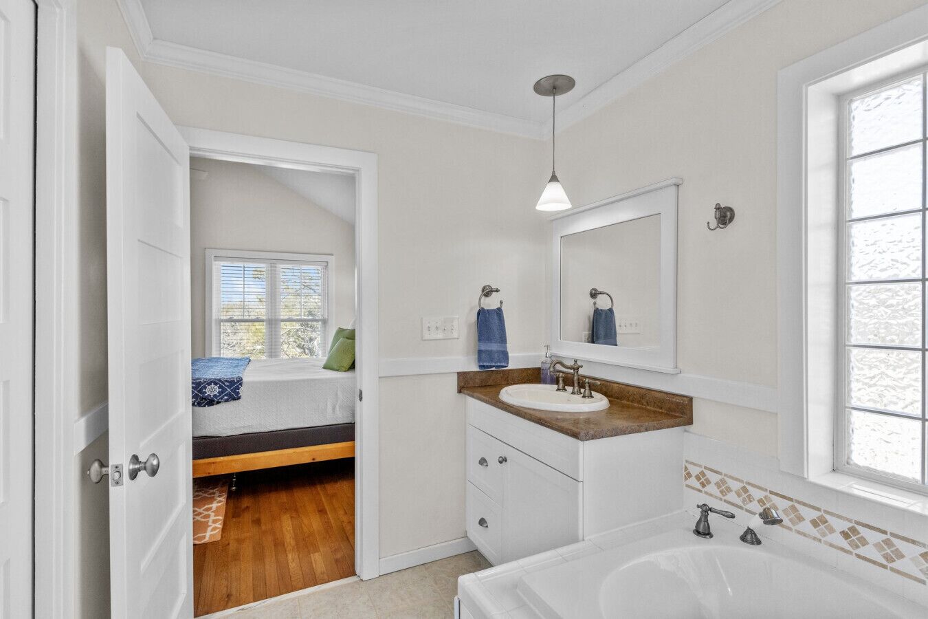 Une salle de bain avec une baignoire, un lavabo doté d’un plan de travail en bois, un miroir et une fenêtre.