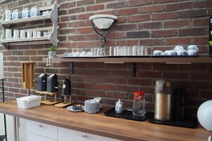 Una encimera de cocina con una cafetera, un hervidor, un tostador y una prensa francesa.